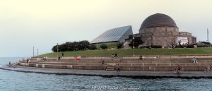 Adler Planetarium and Skyline Walk line Chicago’s Lake Michigan waterfront as people enjoy a summer afternoon along the curved shoreline, with the Art Deco planetarium and glass Sky Pavilion overlooking the water. Located at 1300 South DuSable Lake Shore Drive, the complex combines Ernest A. Grunsfeld Jr.’s original 1930 planetarium with the later pavilion by Lohan Associates – © 2026 David Oppenheimer – Performance Impressions photography archives https://performanceimpressions.com Adler Planetarium and Skyline Walk, Adler Planetarium Skyline Walk, Adler Planetarium, Adler Planetarium Chicago, Skyline Walk, Skyline Walk Chicago, Adler Skyline Walk, Adler Planetarium and Astronomy Museum, 1300 S DuSable Lake Shore Drive, 1300 South DuSable Lake Shore Drive, 1300 S Lake Shore Drive, 1300 South Lake Shore Drive, DuSable Lake Shore Drive, Lake Shore Drive, Museum Campus, Museum Campus Chicago, Northerly Island, Northerly Island Chicago, Northerly Island Park, Solidarity Drive, Near South Side, South Loop, South Loop Chicago, Chicago Illinois, Chicago IL, 60605, Lake Michigan, lake, water, lakefront, waterfront, shoreline, seawall, seawall seating, waterfront seating, lakefront seating, benches, outdoor benches, promenade, walkway, walking path, Lakefront Trail, Chicago Lakefront Trail, people, visitors, tourists, sightseeing, sitting, walking, recreation, outdoors, public space, Chicago lakefront, Chicago waterfront, Lake Michigan waterfront, planetarium, museum, astronomy museum, science museum, space museum, astronomy, science, space, education, attraction, Chicago attraction, tourist attraction, cultural attraction, Chicago museum, first planetarium, historic planetarium, facade, building exterior, exterior, museum exterior, Art Deco, Art Deco facade, granite facade, rainbow granite, copper dome, dome, historic facade, 12 sided building, Sky Pavilion, glass pavilion, curved glass, Doane Observatory, observatory, historic building, landmark building, National Historic Landmark, architecture, architectural photography, Chicago architecture, museum architecture, Art Deco architecture, historic architecture, Ernest A Grunsfeld Jr, Ernest Grunsfeld, Max Adler, Alfonso Iannelli, Lohan Associates, Chicago Park District, Illinois architecture, United States, licensing, image licensing, commercial imagery, photography licensing, art, print, fine art, commercial photography, David Oppenheimer, horizontal, 1-15213827141