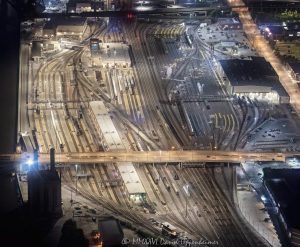 BNSF Metra Railroad Yard and Amtrak Chicago Car Yard night aerial photo in Chicago, Illinois, showing dense railroad tracks, switch tracks, rail yards, and passenger rail infrastructure south of Chicago Union Station. The view includes the Roosevelt Road bridge, Union Station Power House, and rail corridor near South Canal Street in the Near West Side and South Loop area – © 2026 David Oppenheimer – Performance Impressions aerial photography archives https://performanceimpressions.com BNSF Metra Railroad Yard, BNSF Metra yard, BNSF railroad yard, Metra railroad yard, Metra yard, BNSF Chicago, Metra Chicago, Amtrak Chicago Car Yard, Amtrak car yard, Amtrak Chicago, Chicago rail yard, Chicago railroad yard, Chicago train yard, rail yard, railroad yard, train yard, rail tracks, railroad tracks, train tracks, switch tracks, rail switches, track switches, rail junction, railroad junction, rail infrastructure, railroad infrastructure, passenger rail, commuter rail, intercity rail, rail corridor, Chicago Union Station, Union Station, Union Station Power House, Roosevelt Road bridge, Roosevelt Road, 1231 South Canal, 1231 South Canal Street, 1231 S Canal, South Canal Street, Canal Street, 60607, Chicago, Chicago Illinois, Illinois, United States, Near West Side, South Loop, downtown Chicago, aerial, night aerial, aerial photo, aerial photograph, aerial photography, aerial photographer, aerial view, aerial image, nighttime aerial, night photography, night photo, railroad photography, rail photography, transportation photography, infrastructure photography, transportation, transportation infrastructure, urban infrastructure, industrial infrastructure, railway, railroad, trains, Metra, BNSF, Amtrak, bridge, overpass, city lights, lighting, rail lighting, commercial photography, commercial imagery, image licensing, licensing, photography licensing, David Oppenheimer, 1-15156784411