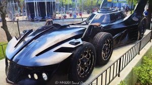 Six-wheel Batmobile at Six Flags Great America near Chicago in Gurnee, Illinois, shown in close-up in the amusement park’s DC Universe themed area. The futuristic black Batman vehicle features a multi-axle design with four closely spaced front wheels, an aircraft-style cockpit canopy, tall vertical batwing fins and multiple exposed exhaust pipes, creating a distinctive comic-book-inspired interpretation of Batman’s iconic car – © 2026 David Oppenheimer – Performance Impressions photography archives https://performanceimpressions.com Batmobile, Six Flags Batmobile, Six Flags Great America Batmobile, Great America Batmobile, Batman Batmobile, Batmobile Chicago, Chicago Batmobile, Batmobile Illinois, six-wheel Batmobile, six-wheeled Batmobile, six wheels, six-wheel vehicle, six-wheeled vehicle, multi-axle, multi-axle vehicle, dual front axle, twin front axle, front axles, four front wheels, Batman car, Batman vehicle, Batmobile car, Batmobile vehicle, Batmobile display, Batman display, vehicle display, display vehicle, show car, superhero car, superhero vehicle, futuristic Batmobile, futuristic car, futuristic vehicle, custom car, custom vehicle, black Batmobile, black car, black vehicle, automobile, automotive, car, vehicle, transportation, automotive design, vehicle design, futuristic design, aerodynamic, aerodynamic design, bodywork, sculpted bodywork, vehicle exterior, car exterior, exterior, close up, close-up, detail, vehicle detail, automotive detail, wheels, wheel, tires, tire, wheel design, front wheels, cockpit, cockpit canopy, aircraft-style cockpit, aircraft cockpit, canopy, enclosed cockpit, windshield, windscreen, batwing fins, bat wings, rear fins, vertical fins, tail fins, Batman fins, exhaust, exhaust pipes, eight exhaust pipes, multiple exhausts, side exhaust, exhaust detail, pipes, side intakes, air intakes, vents, Batman, BATMAN, Batman DC, DC Batman, DC Comics, DC Comics Batman, DC, DC Universe, Six Flags DC Universe, DC Universe Six Flags, Great America DC Universe, DC Universe Chicago, DC Universe Illinois, superhero, superheroes, DC superhero, comic book, comics, comic books, comic character, comic superhero, superhero icon, Batman icon, Batman memorabilia, DC memorabilia, Batman attraction, Batman theme, Batman themed, Batman experience, themed vehicle, themed entertainment, comic-book inspired, comic inspired, fantasy vehicle, fictional vehicle, entertainment vehicle, photo op, Six Flags Great America, Six Flags Great America Chicago, Great America Chicago, Great America Illinois, Six Flags Chicago, Six Flags Illinois, Six Flags, Great America, amusement park, theme park, amusement parks, theme parks, amusement park attraction, theme park attraction, park attraction, attraction, attractions, entertainment, family entertainment, tourist attraction, travel destination, destination, Gurnee, Gurnee Illinois, Gurnee IL, Illinois, Lake County, Lake County Illinois, northern Illinois, Chicagoland, Chicago area, Chicago, Chicago Illinois, Chicago attraction, Chicago attractions, Chicago theme park, Chicago amusement park, Chicago tourism, Chicago travel, Chicago trip, Chicago vacation, Visit Chicago, visit Chicago, Illinois attraction, Illinois attractions, Illinois tourism, Illinois travel, Visit Illinois, Midwest, Midwest attraction, Midwest amusement park, Midwest theme park, tourism, travel, sightseeing, vacation, summer, summer travel, Great America Parkway, 1 Great America Parkway, Grand Avenue, Route 132, Interstate 94, I-94, 60031, United States, USA, Warner Bros, Warner Brothers, Warner Bros Discovery, Warner Bros. Discovery, WBD, Warner Bros Themed Entertainment, DC Studios, Six Flags Entertainment Corporation, Six Flags Entertainment, Six Flags company, Six Flags stock, FUN, NYSE FUN, Cedar Fair, amusement park photography, theme park photography, Batmobile photography, Batman photography, DC photography, superhero photography, automotive photography, car photography, vehicle photography, detail photography, entertainment photography, travel photography, tourism photography, editorial photography, commercial photography, fine art photography, Batmobile art, Batman art, superhero art, DC art, automotive art, car art, vehicle art, Six Flags art, Great America art, Chicago art, Batmobile print, Batman print, superhero print, automotive print, car print, photographic print, fine art print, archival print, gallery print, collector print, wall art, office art, licensing, image licensing, commercial imagery, photography licensing, art, print, fine art, commercial photography, David Oppenheimer, Performance Impressions, Performance Impressions photography archives, horizontal, 1-15156784411