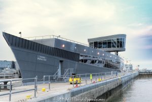 Chicago Harbor Lock Control House at the mouth of the Chicago River features a ship-inspired zinc-clad exterior and glass control tower overlooking the navigation passage to Lake Michigan. The Chicago Harbor entrance and breakwater are visible beyond the modern facility, which CTE AECOM designed for the U.S. Army Corps of Engineers in Chicago, Illinois – © 2026 David Oppenheimer – Performance Impressions photography archives https://performanceimpressions.com